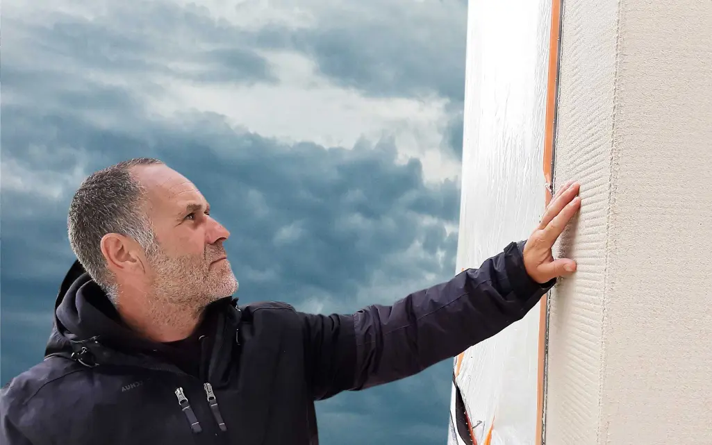 Fachhandwerker streicht über verputzte Fassade, gedämmt und beschichtet mit Sto-Produkten