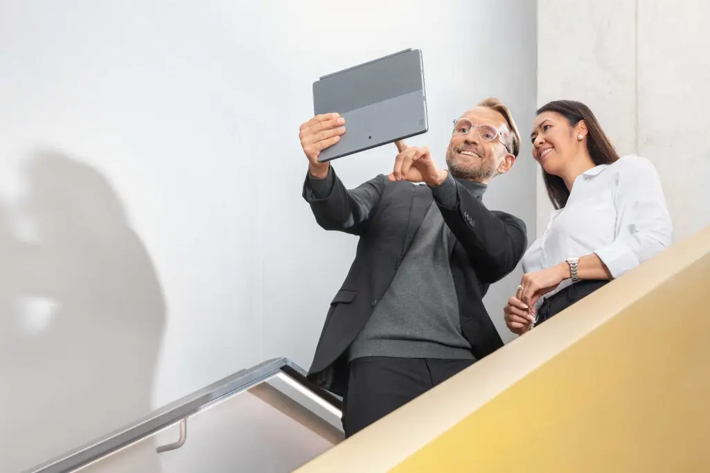 Foto: Beratungsszene Mann/Frau auf einer Treppe: Berater von Sto zeigt auf Tablet, daneben Kundin