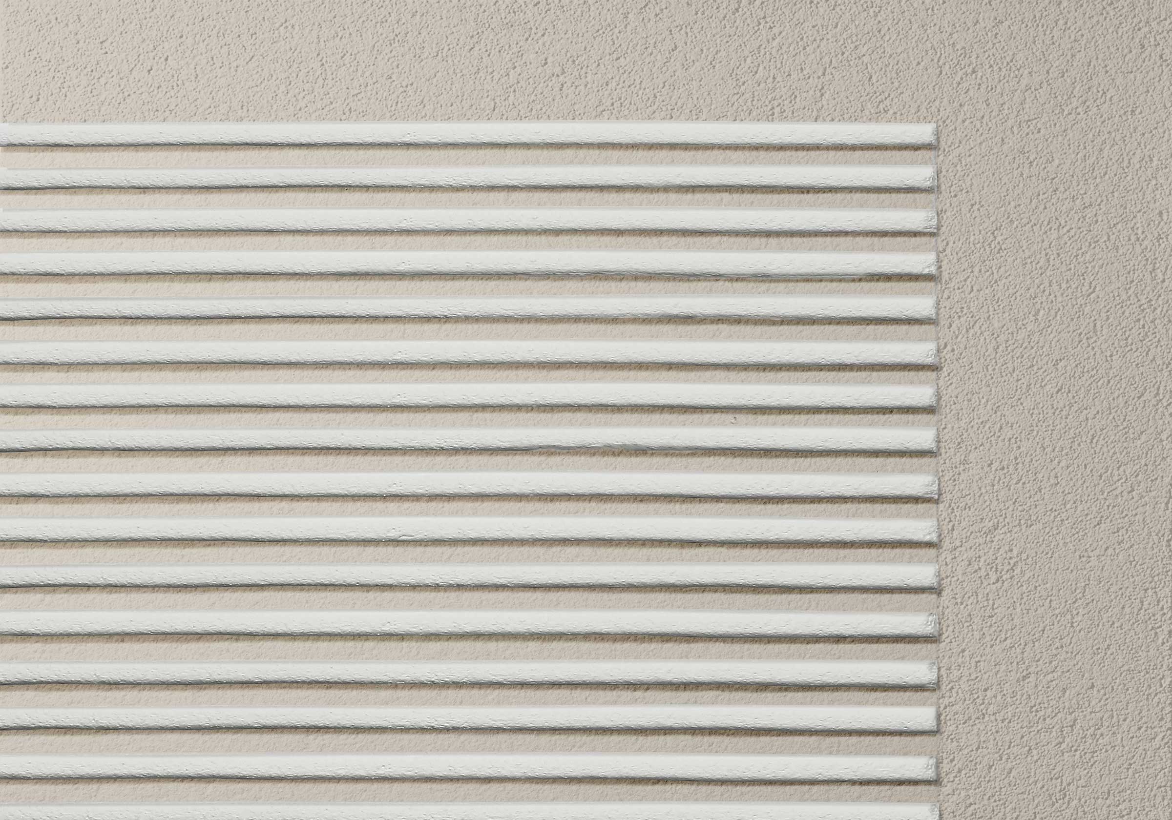 Detailaufnahme einer beigefarbenen, gedämmten Fassade mit linearer StoSignature Putztextur