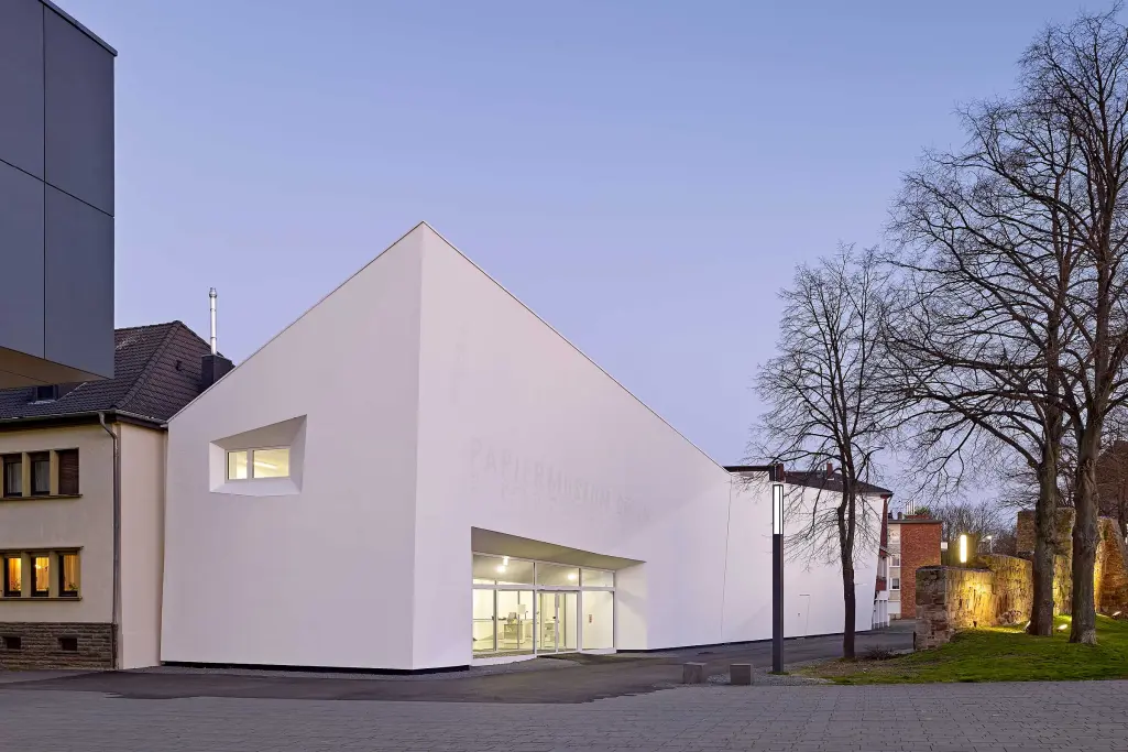 Foto, Dämmerungsaufname des Papiermuseums in Düren, weiße Fassade, beschichtet mit Sto-Produkten