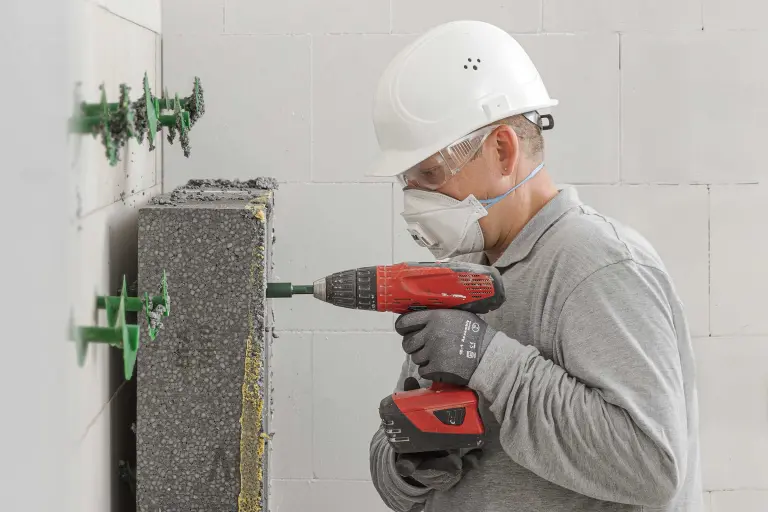 Kreislaufwirtschaft: Handwerker mit Maske testet Rückbau von Dämmstoffen mit Dübel StoFix Circonic