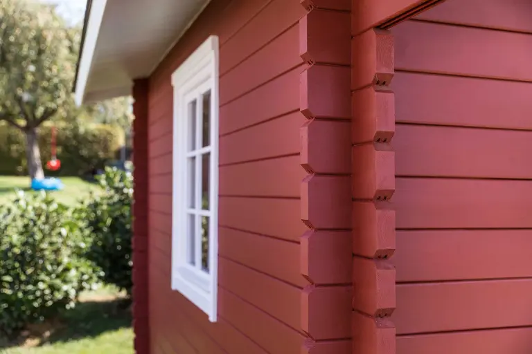Detail-Außenaufnahme eines roten Gartenhäuschens, beschichtet mit bionischer Fassadenfarbe StoColor Dryonic® Wood