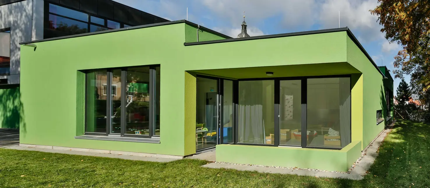 Grüne Fassade einer Kita, gedämmt mit StoTherm Wood: WDVS mit Holzfaserdämmung