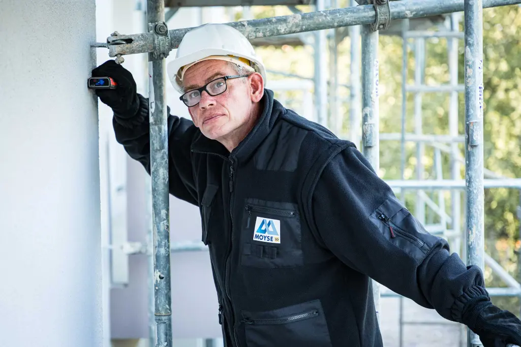 Portrait Fachhandwerer Xavier Deschamps beim Arbeiten an der Fassade, auf dem Gerüst.