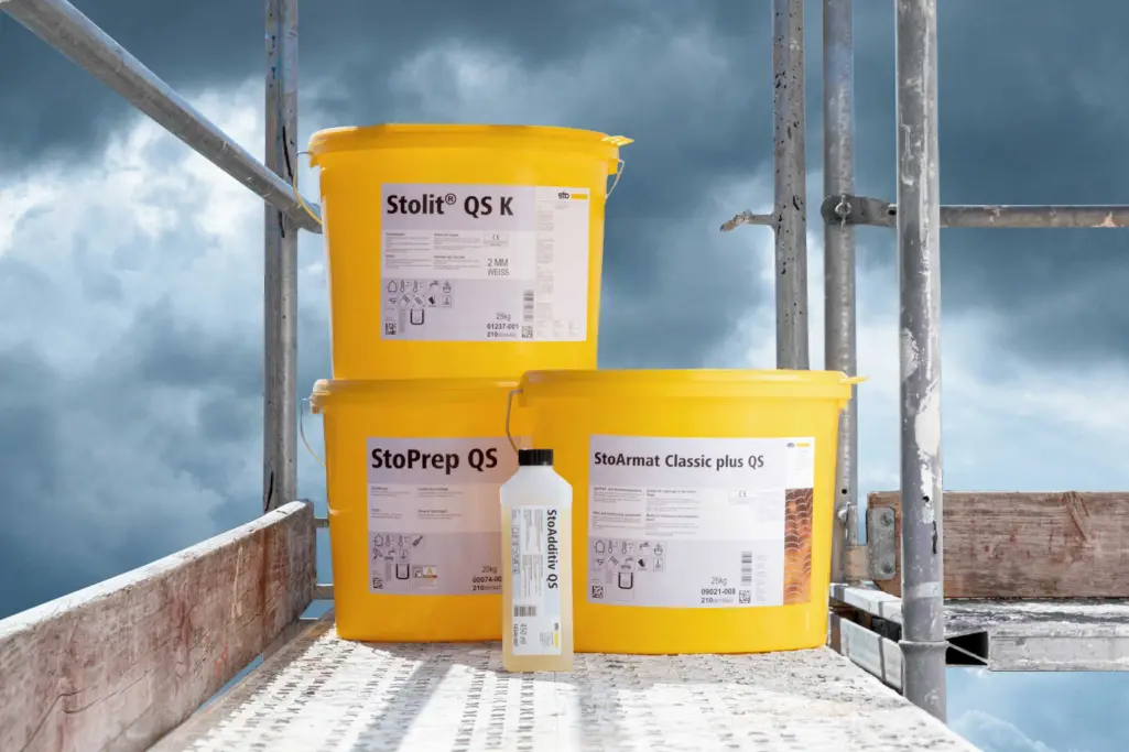QS-Produkte: 3 gelbe Eimer mit QS-Produkten von Sto und eine Flasche StoAdditiv QS auf einem Gerüst