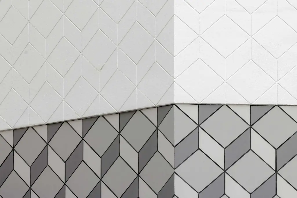 Detailaufnahme Fassade Sporthaus: weißer Putz und graue Keramikfliesen von Sto