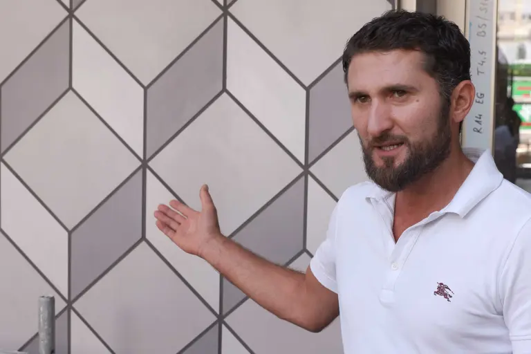 Außergewöhnliche Putz-/Keramikfassade in Grau, daneben Fachhandwerker