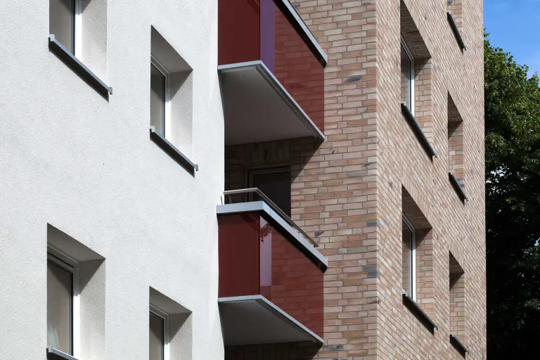 Außenaufnahme eines Wohnhauses, gedämmte Fassade, weiß verputzt und verkleidet mit beigefarbenen Flachverblendern von Sto