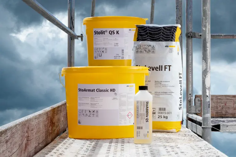 Gerüst mit Produkten für die nasskalte Zeit darauf: zwei gelbe Sto-Eimern und ein Sack mit Putzen ls