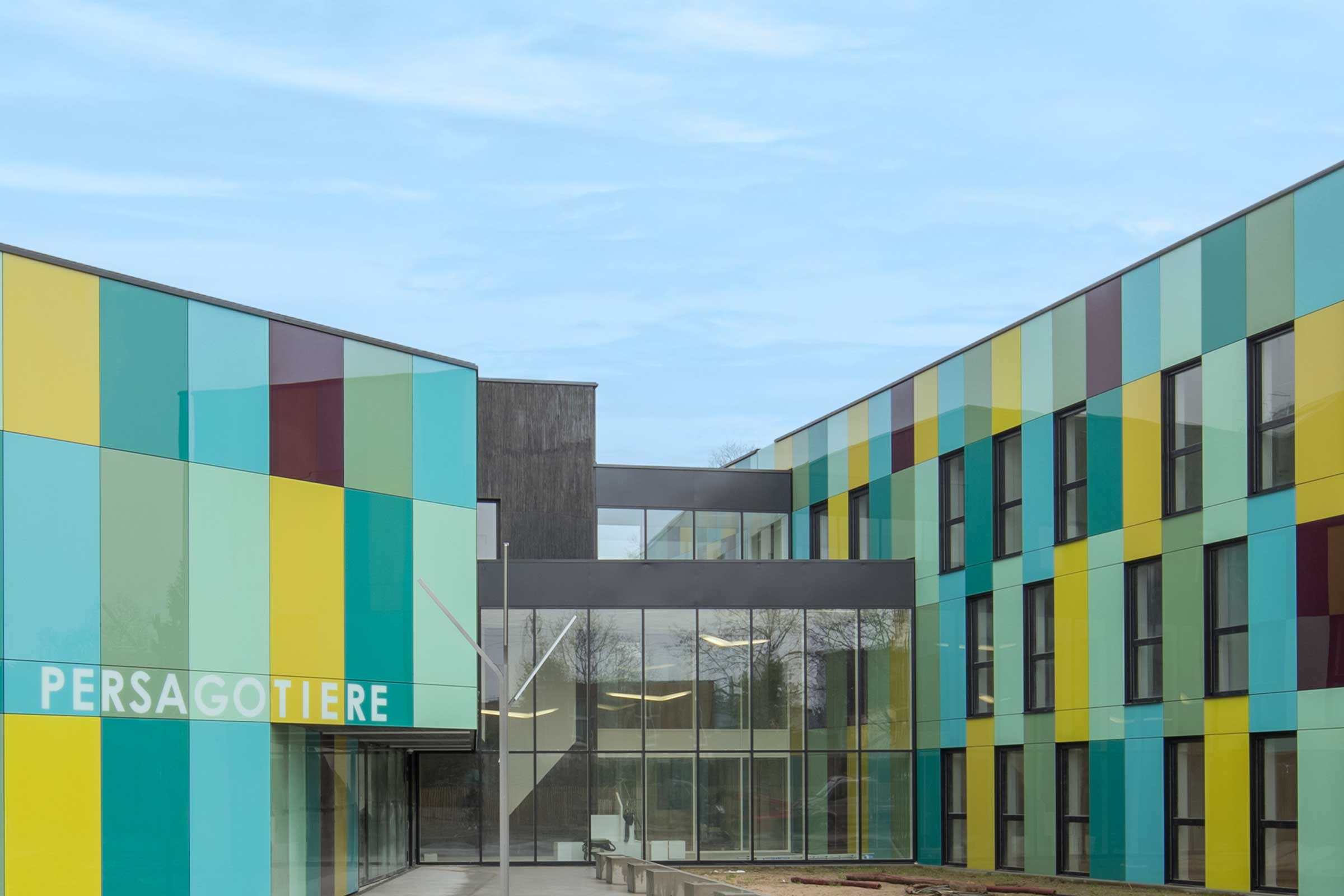 Vorgehängte hinterlüftete Fassade mit Glaspaneelen in Blau, Grün und Gelb. VHF StoVentec Glass