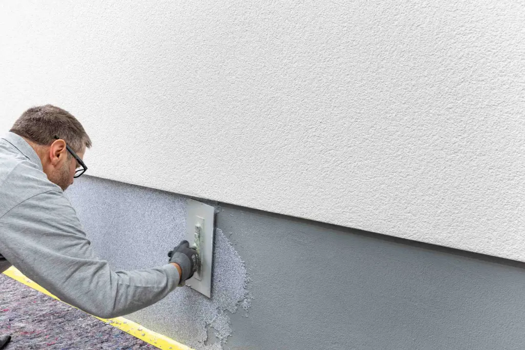 Sockelputz StoSuperlit® schützt vor Witterung. Auftrag des Natursteinputzes mit der Traufel