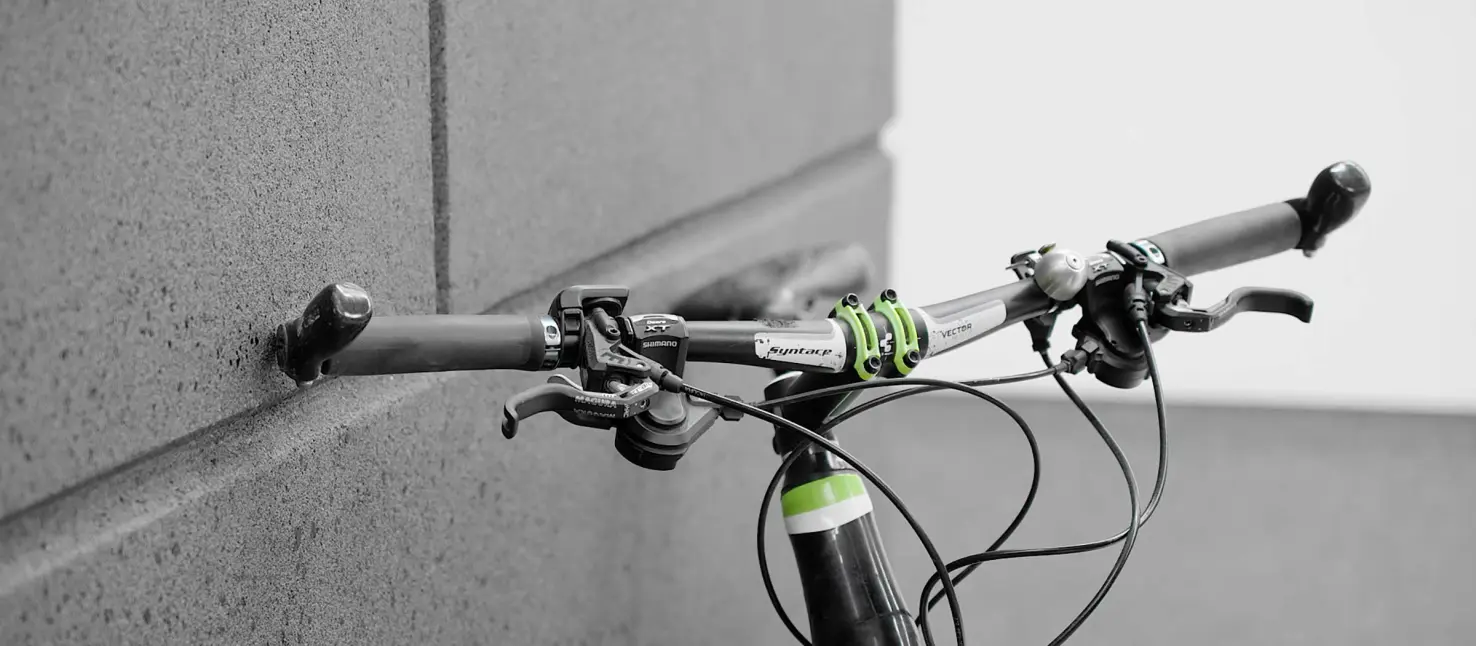 Robuster Buntsteinputz: Fahrradlenker lehnt an der anthrazitfarben Hausfassade