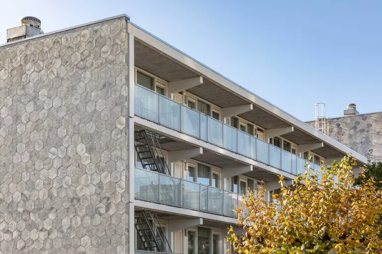 Außenaufnahme eines Mehrfamilienhauses, graue gedämmte Fassade mit vorgefertigten Putzelementen StoEcoshape