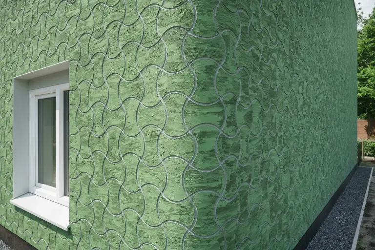 Außenaufnahme, Detailaufnahme einer gedämmten, grünen Hausfassade, bekleidet mit vorgefertigten Putzelementen StoEcoshapes