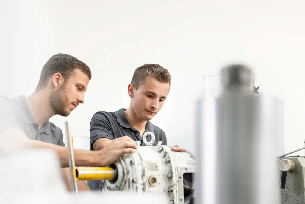 Junger DH-Student bei Sto mit Ausbilder an einer Maschine: Studiengang Maschinenbau