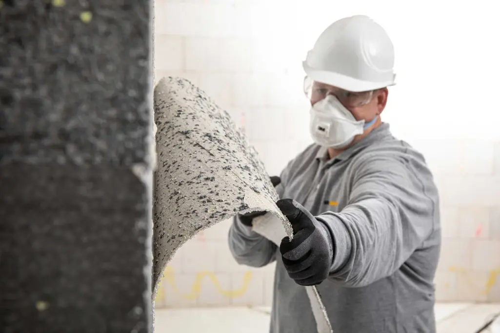 Rückbau von WDVS, Handwerker entfernt bestehendes WDVS, trägt Helm und Maske, Kreislaufwirtschaft