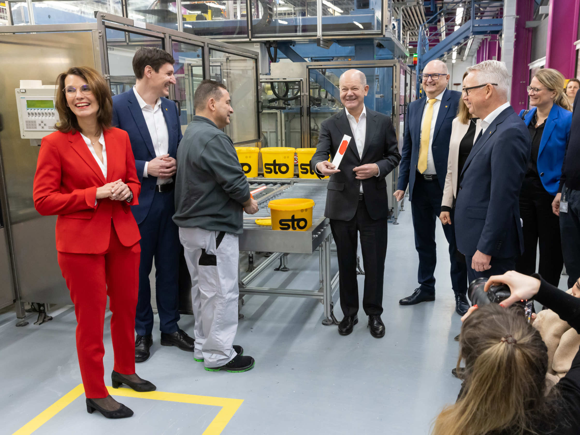 Bundeskanzler Olaf Scholz nimmt eine Farbprobe in der Farbenproduktion von Sto.