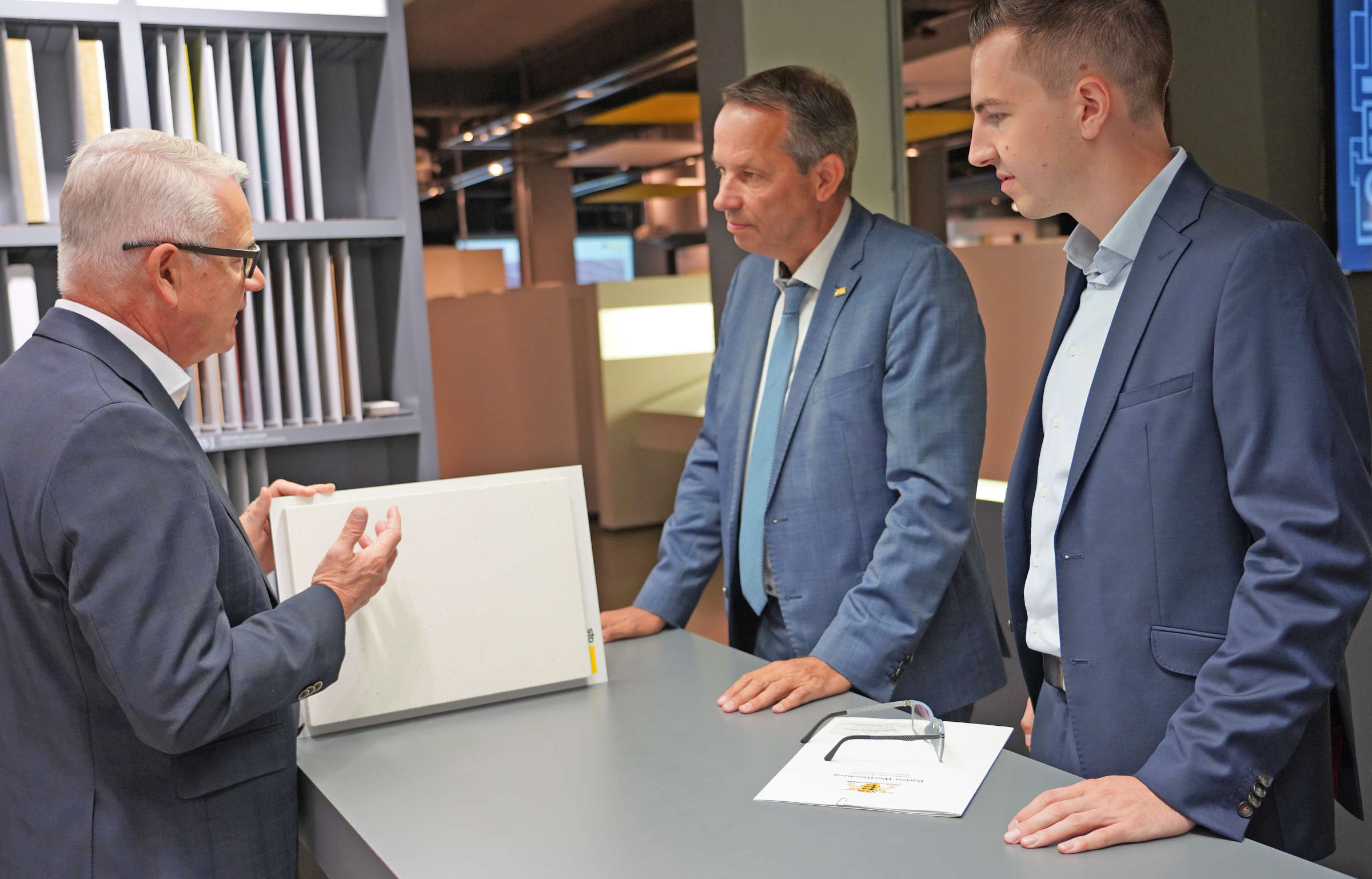 Drei Männer im Sto-Werk stehen um Tisch mit Produktmustern
