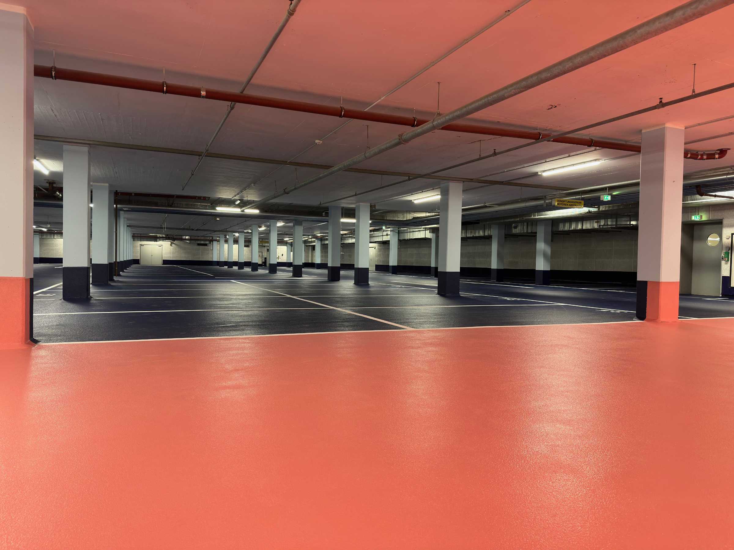 Tiefgarage der Kaufmännische Krankenkasse, Hannover. Schwarze Parkflächen und rote Bodenflächen