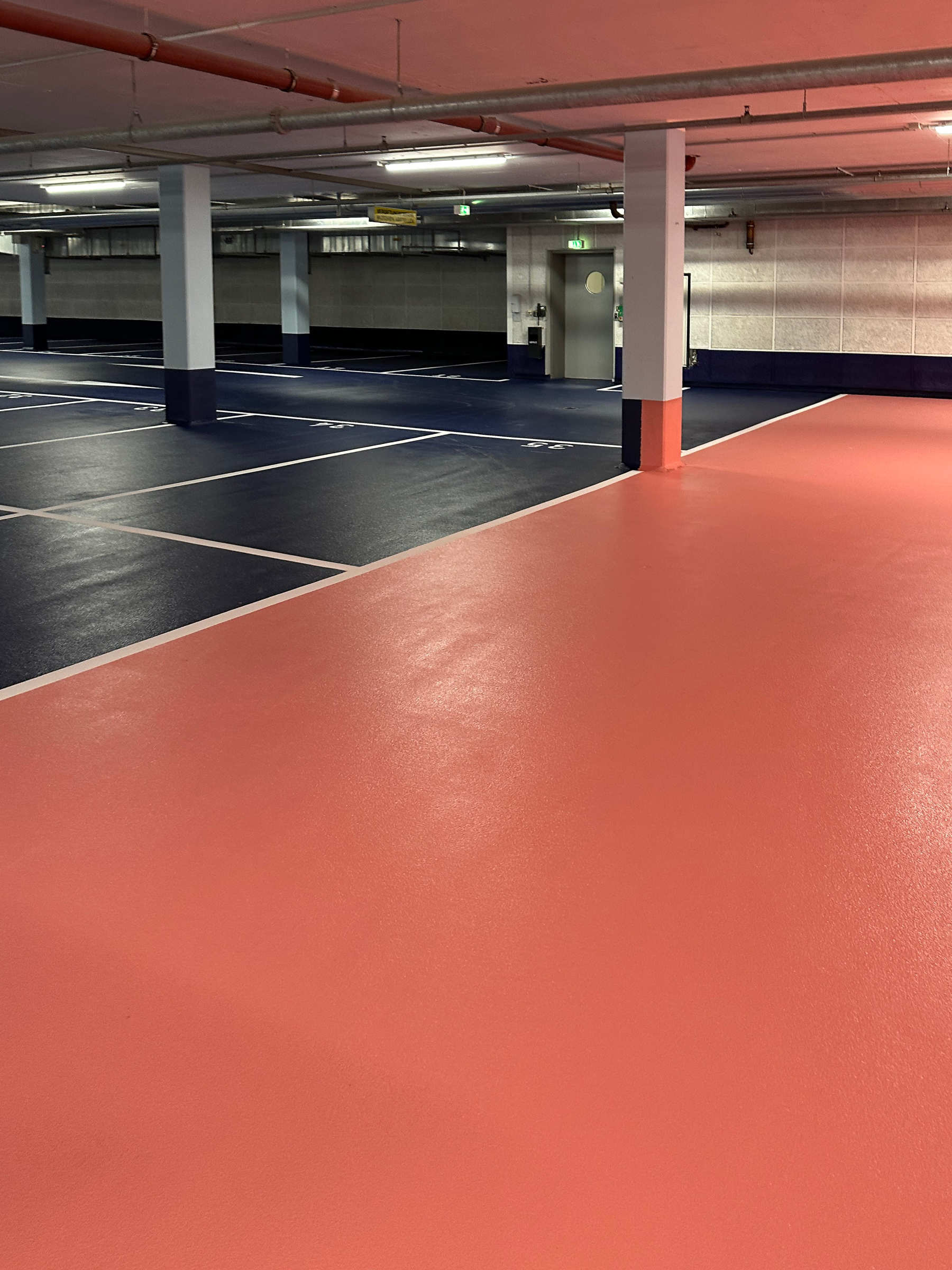 Tiefgarage der Kaufmännische Krankenkasse, Hannover. Schwarze Parkflächen und rote Bodenflächen