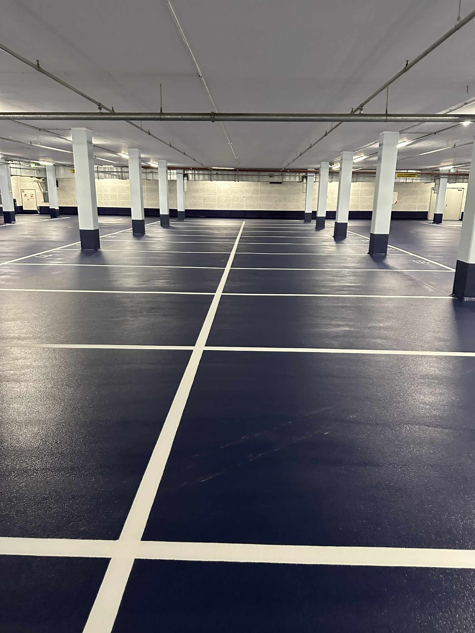 Tiefgarage der Kaufmännische Krankenkasse, Hannover. Schwarze Parkflächen und rote Bodenflächen