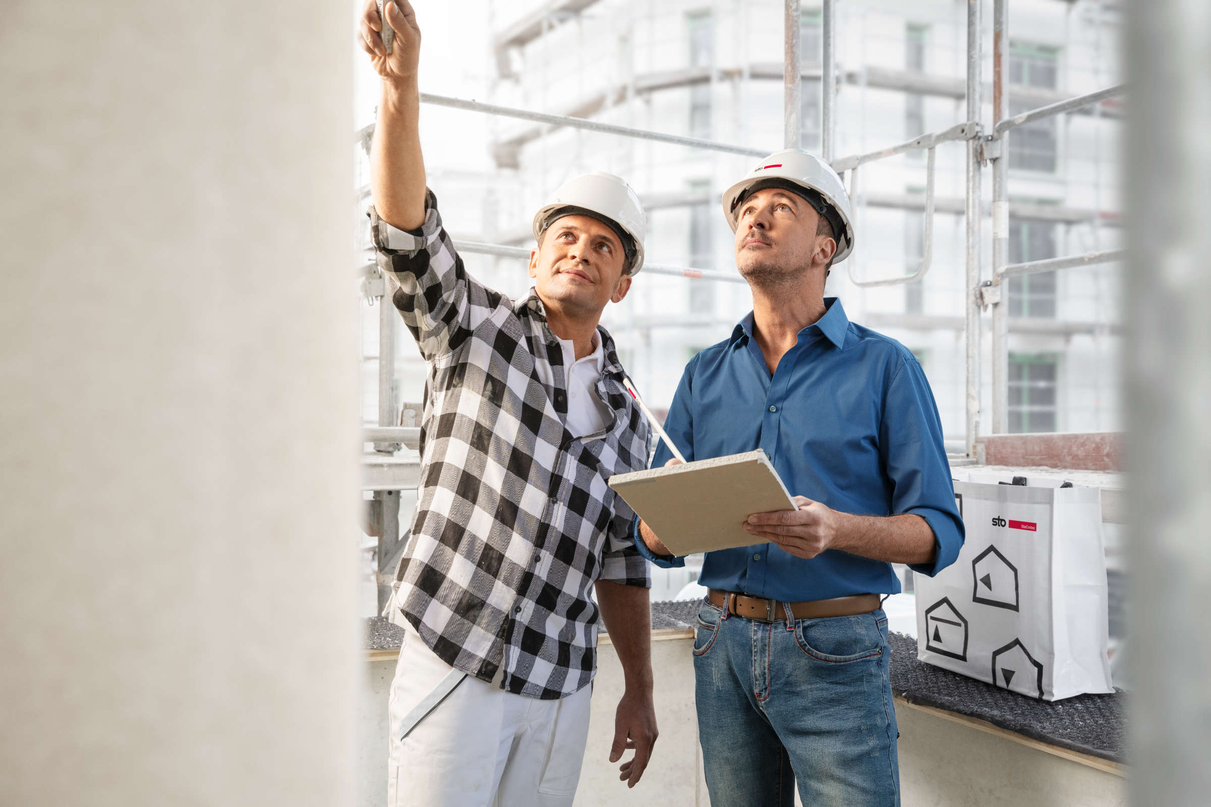 Zwei Männer auf Baustelle begutachten Betonfassade.