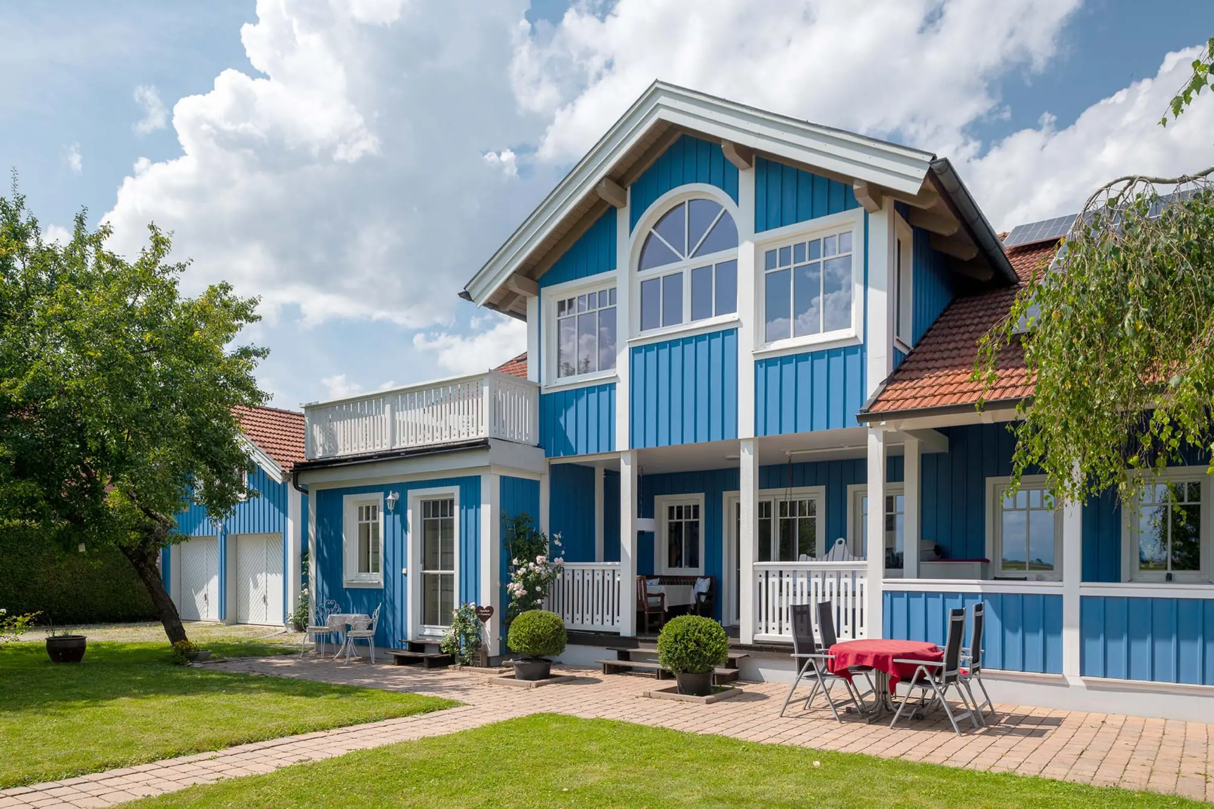 Aufnahme eines blauen Einfamilienhaus mit Garten, Fassaden-Sanierung mit StoColor Dryonic® Wood