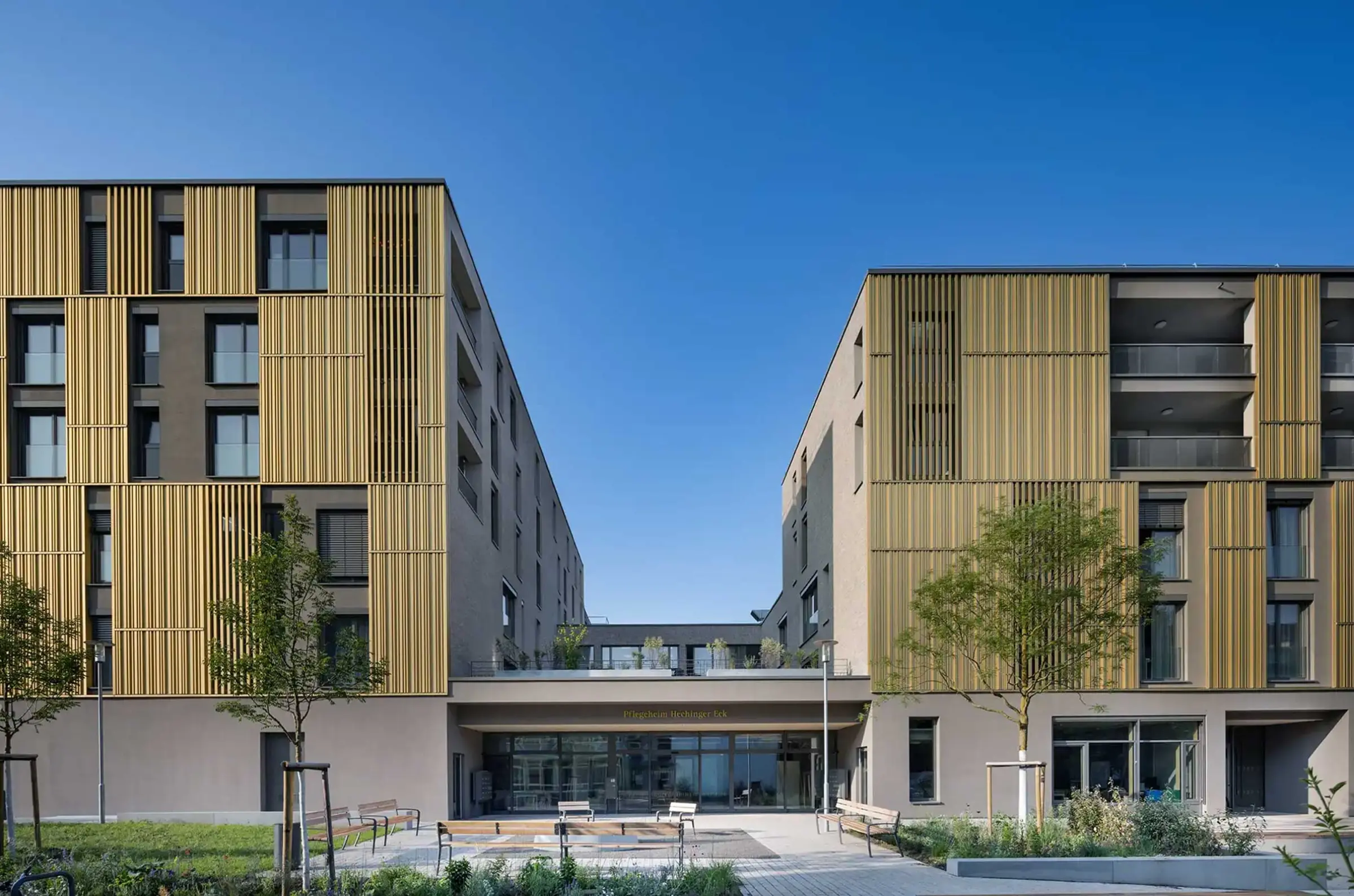 Wohn- und Geschäftsgebäude in Erdtönen mit Sto-Wärmedämmung und goldenen Architekturelementen