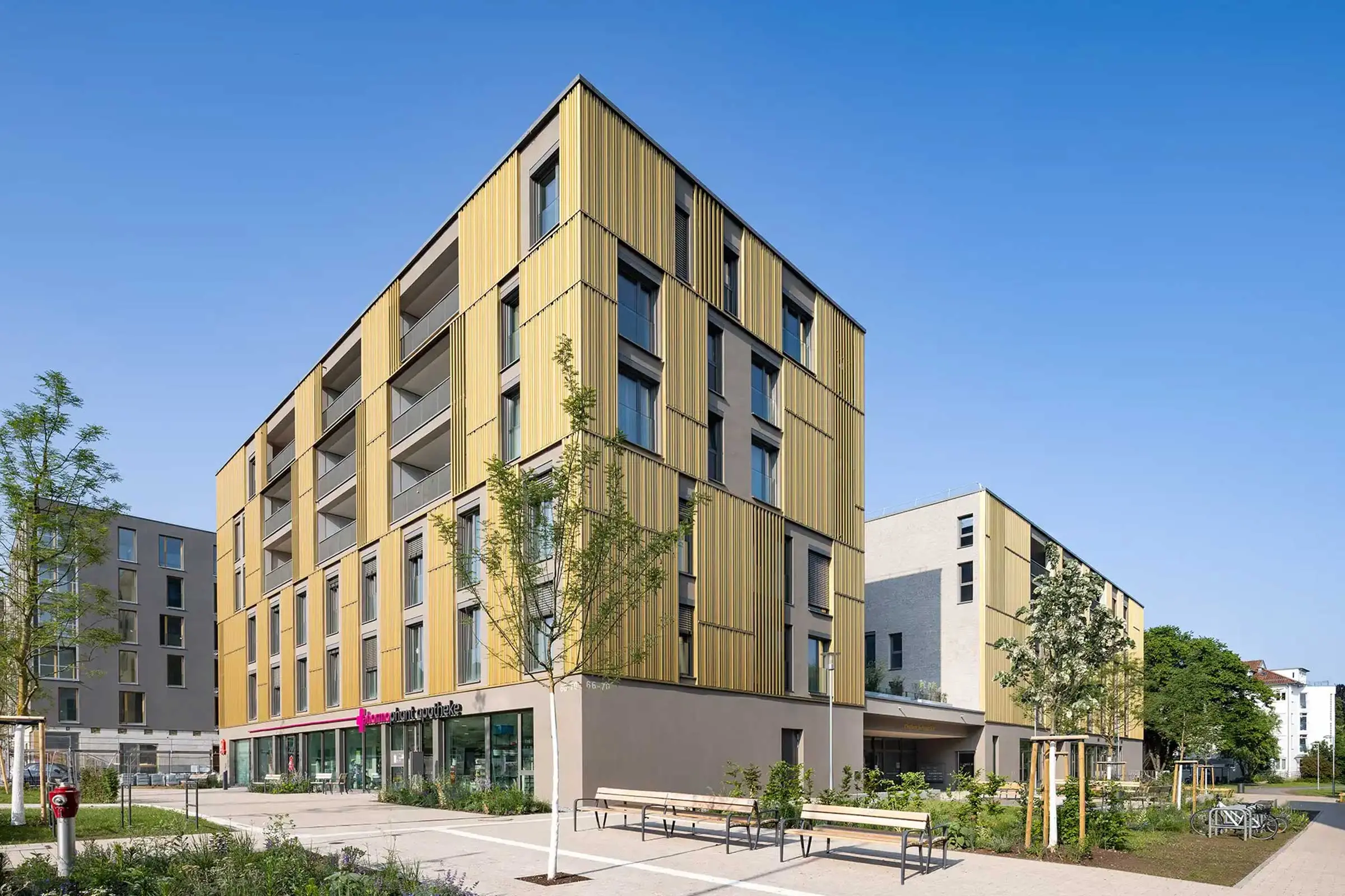 Wohn- und Geschäftsgebäude in Erdtönen mit Sto-Wärmedämmung und goldenen Architekturelementen