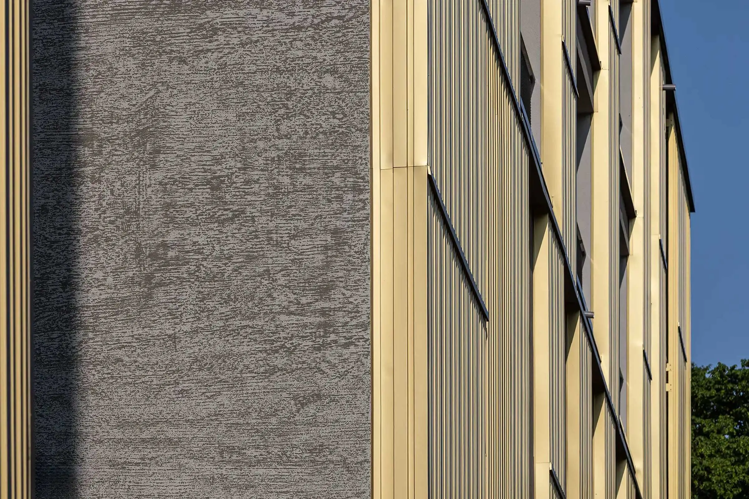 Wohn- und Geschäftsgebäude in Erdtönen mit Sto-Wärmedämmung und goldenen Architekturelementen