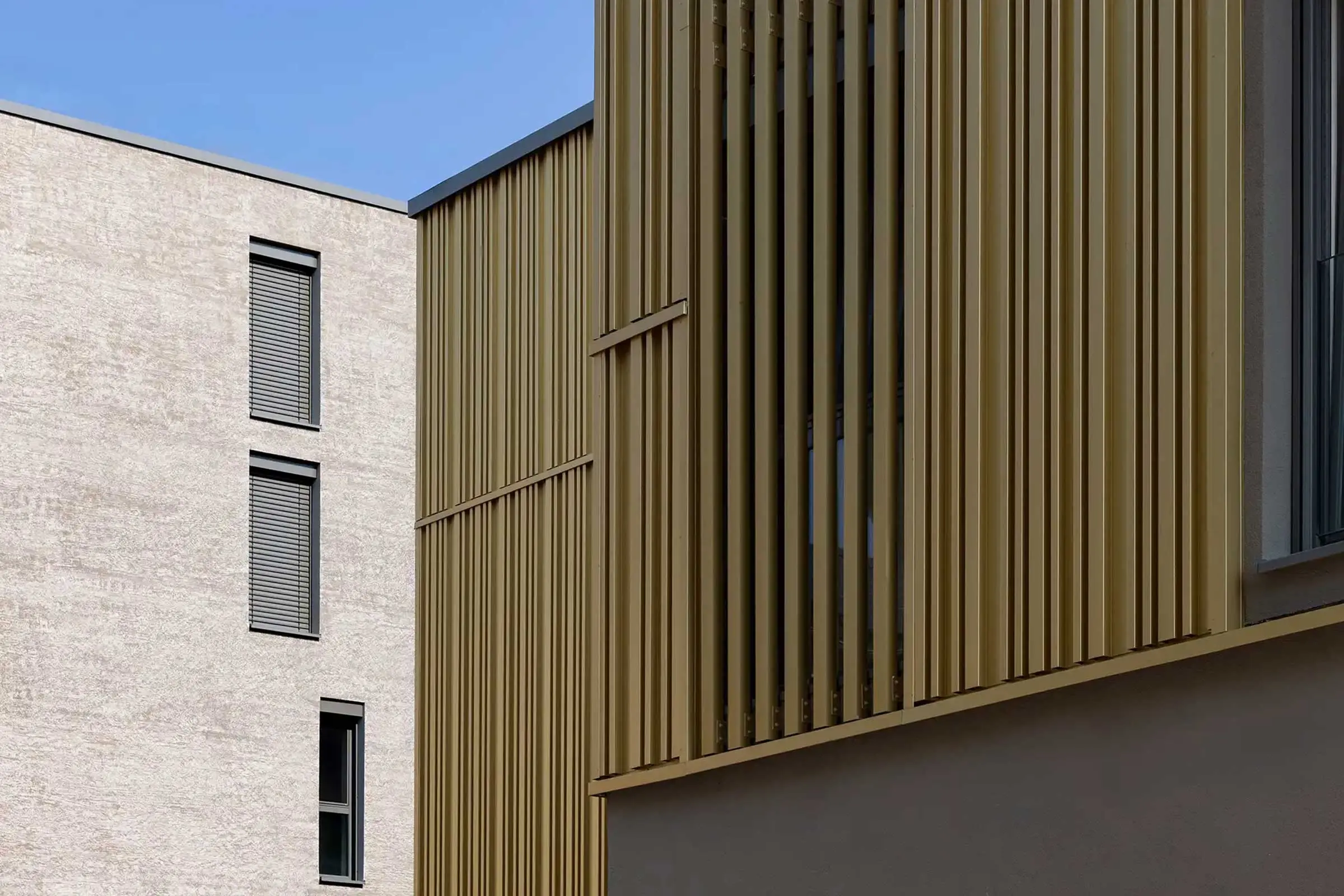 Wohn- und Geschäftsgebäude in Erdtönen mit Sto-Wärmedämmung und goldenen Architekturelementen