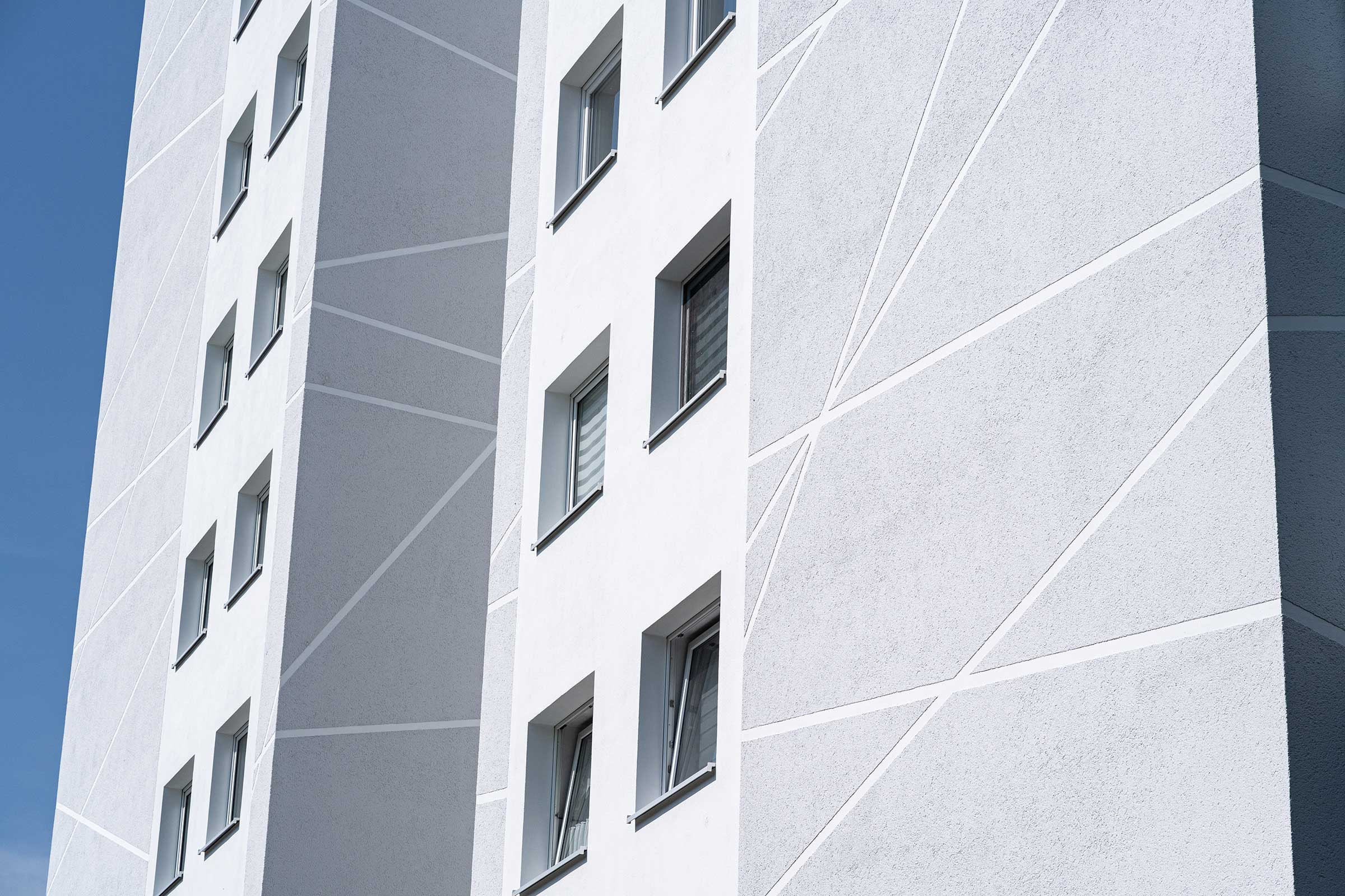 Detailaufnahme Hochhaus mit weiß-grauer Fassade, saniert mit WDVS, Fassadenputz und -farbe von Sto