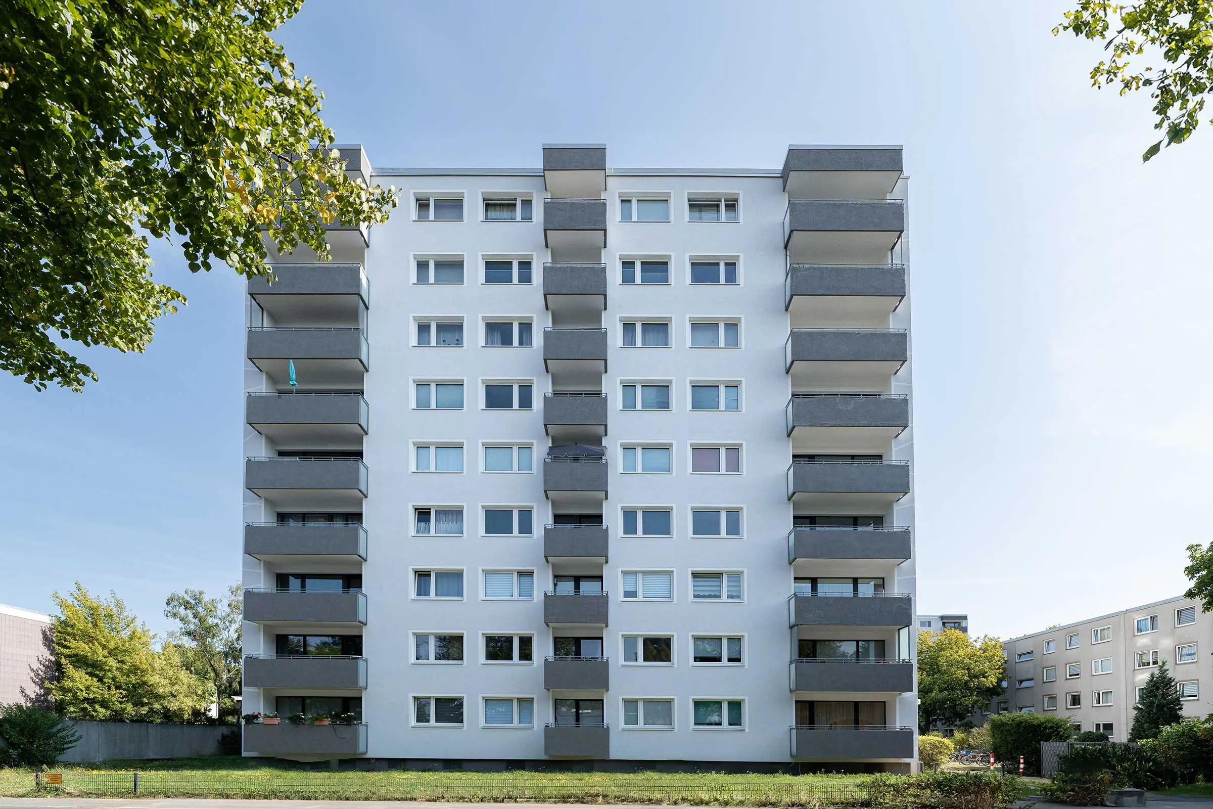 Hochhaus mit weiß-grauer Fassade, saniert mit WDVS, Fassadenputz und -farbe von Sto