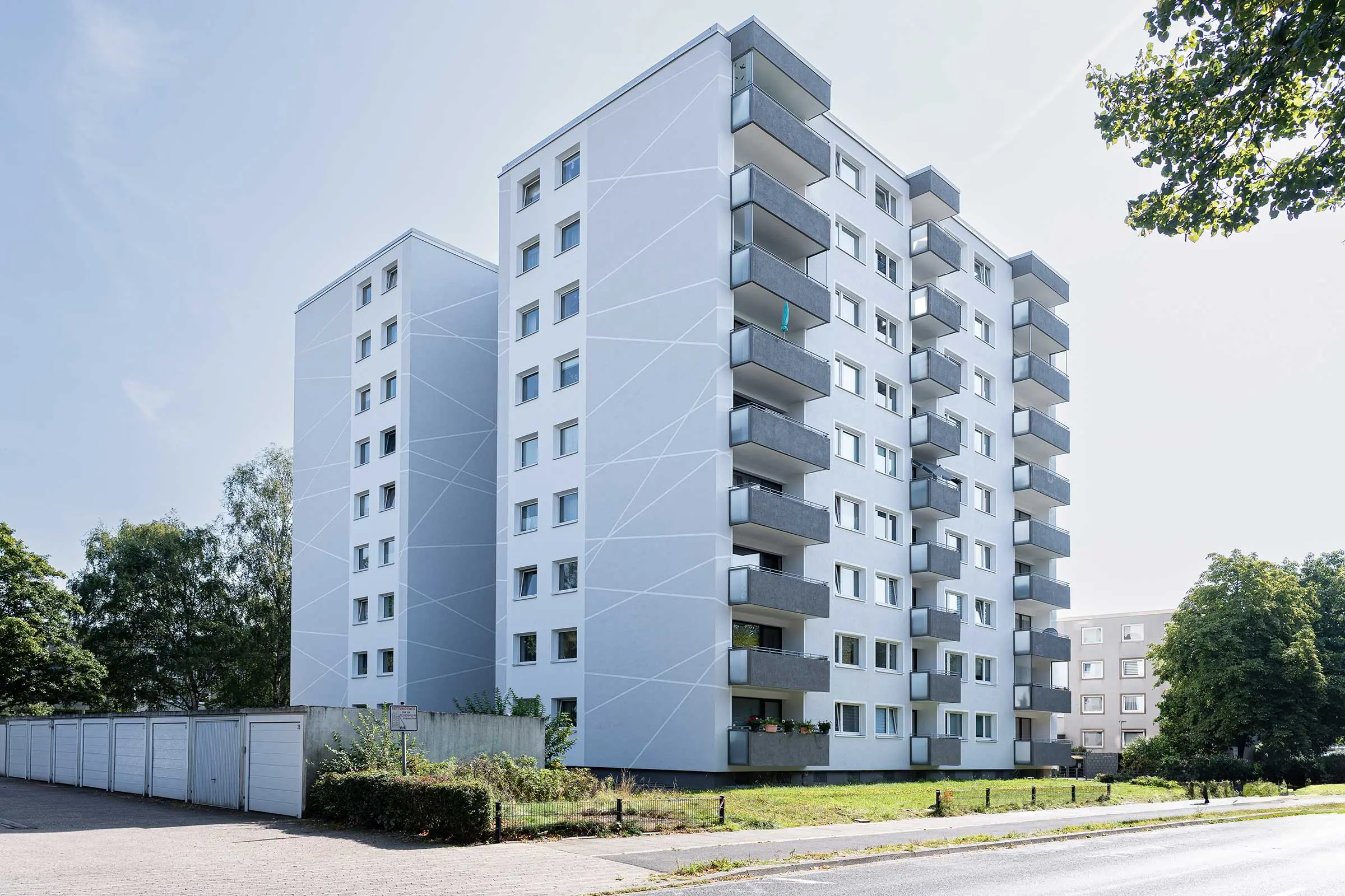 Hochhaus mit weiß-grauer Fassade, saniert mit WDVS, Fassadenputz und -farbe von Sto