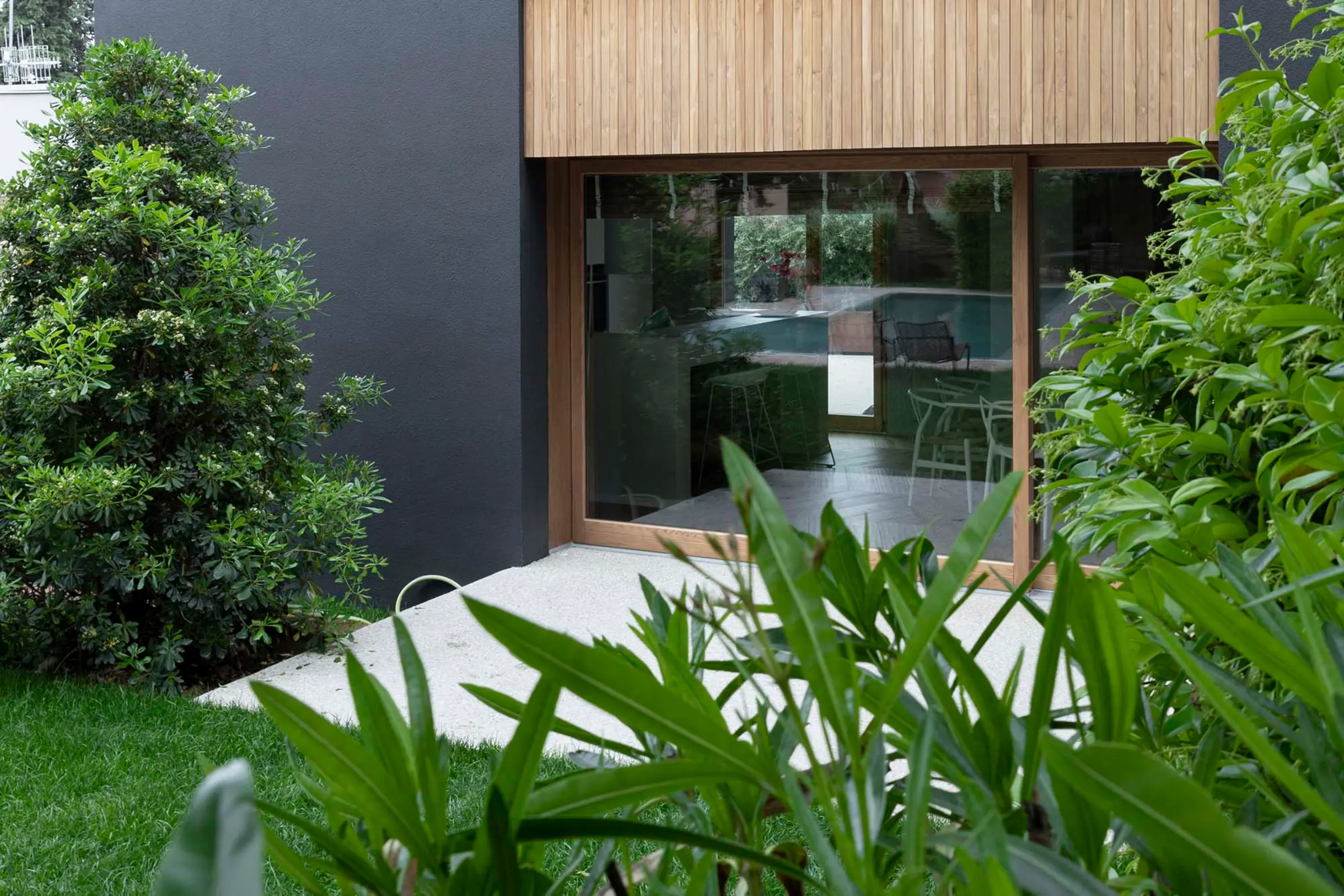 Aufnahme eines Einfamilienhauses in mitten von Grünpflanzen, schwarze Fassade mit X-black Technology