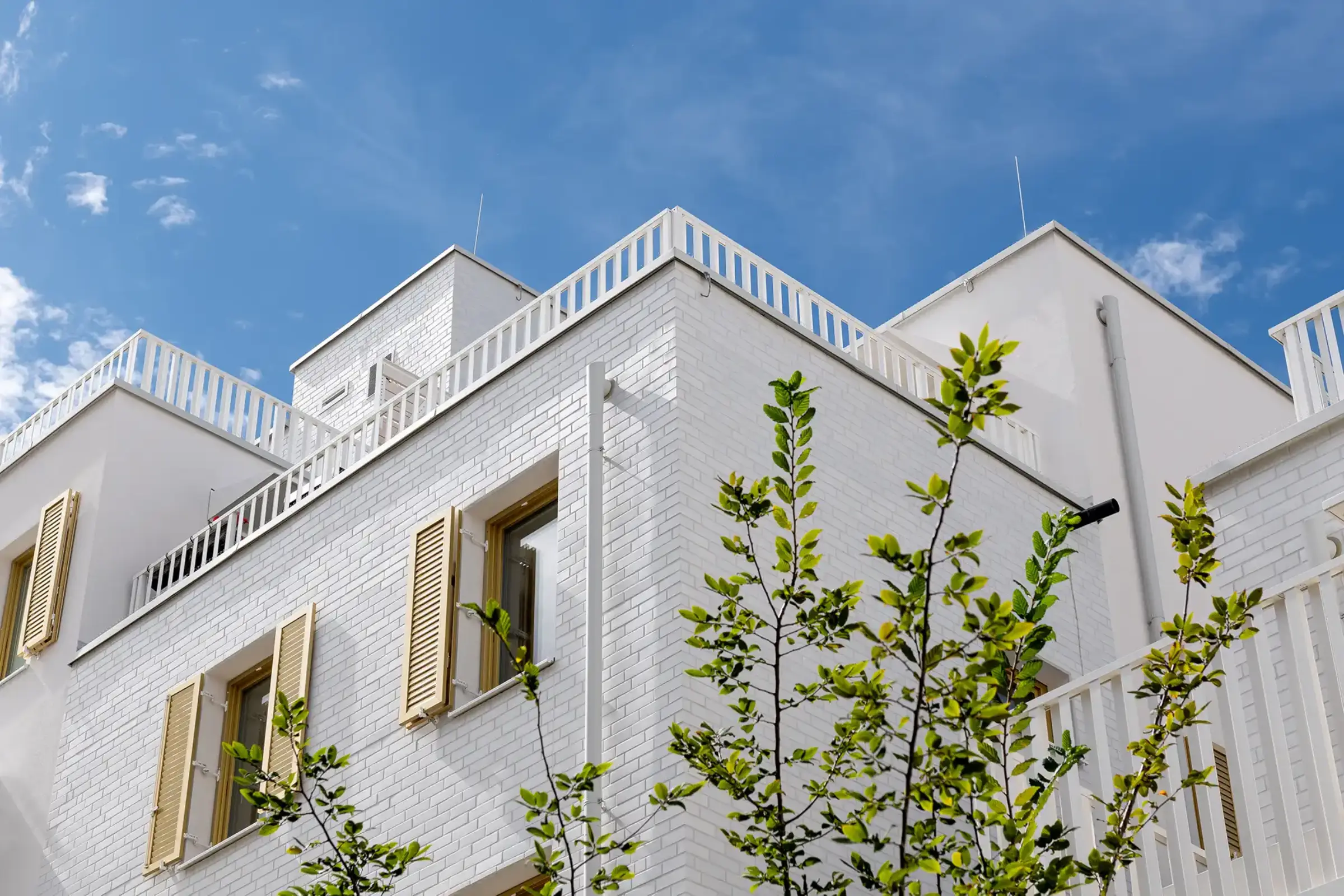 Aufnahme eines Wohnparks, Weiße Klinkerfassaden und goldene Fensterläden