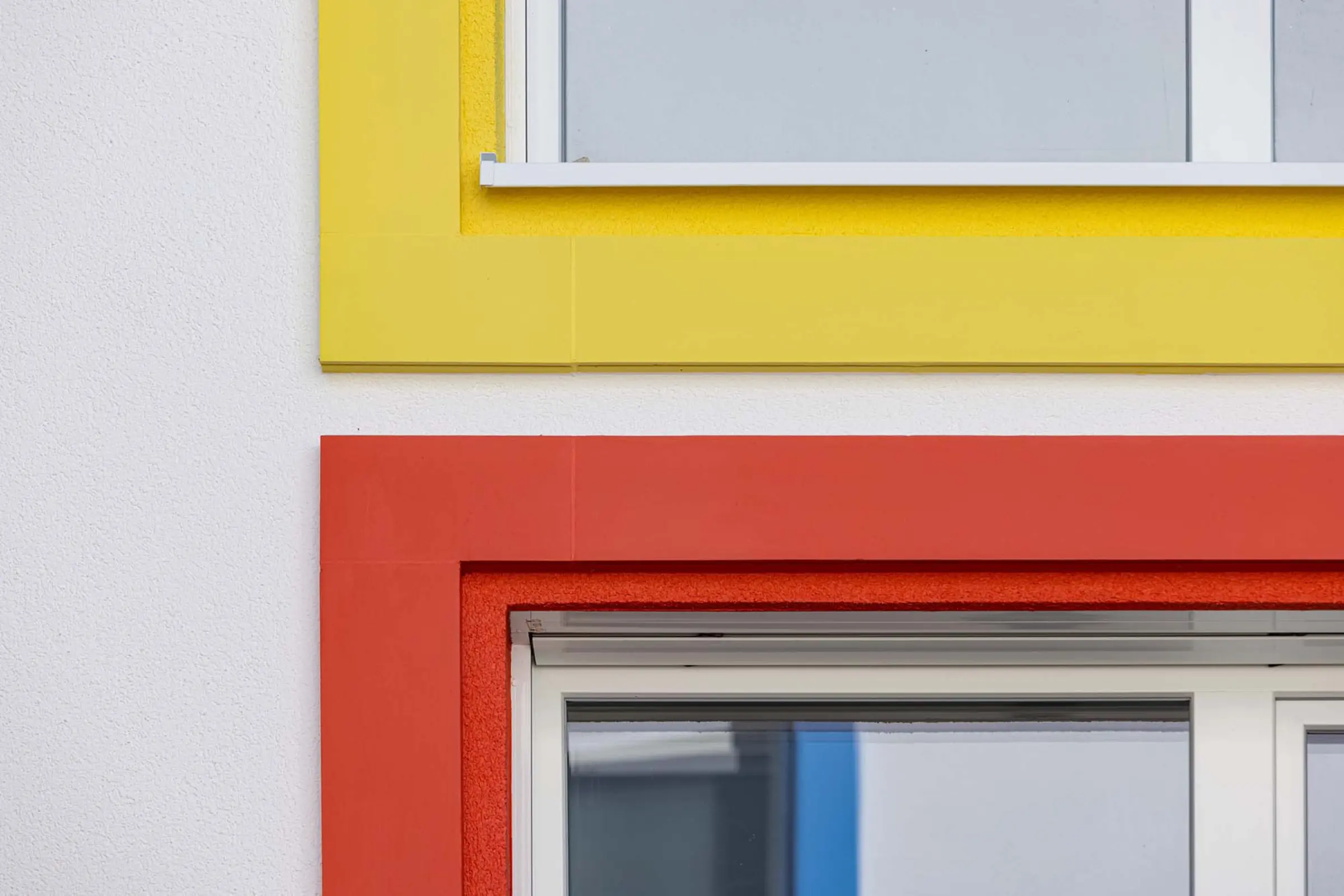 Detailaufnahme der bunten Fensterumrandungen aus StoDeco Fassadenelementen
