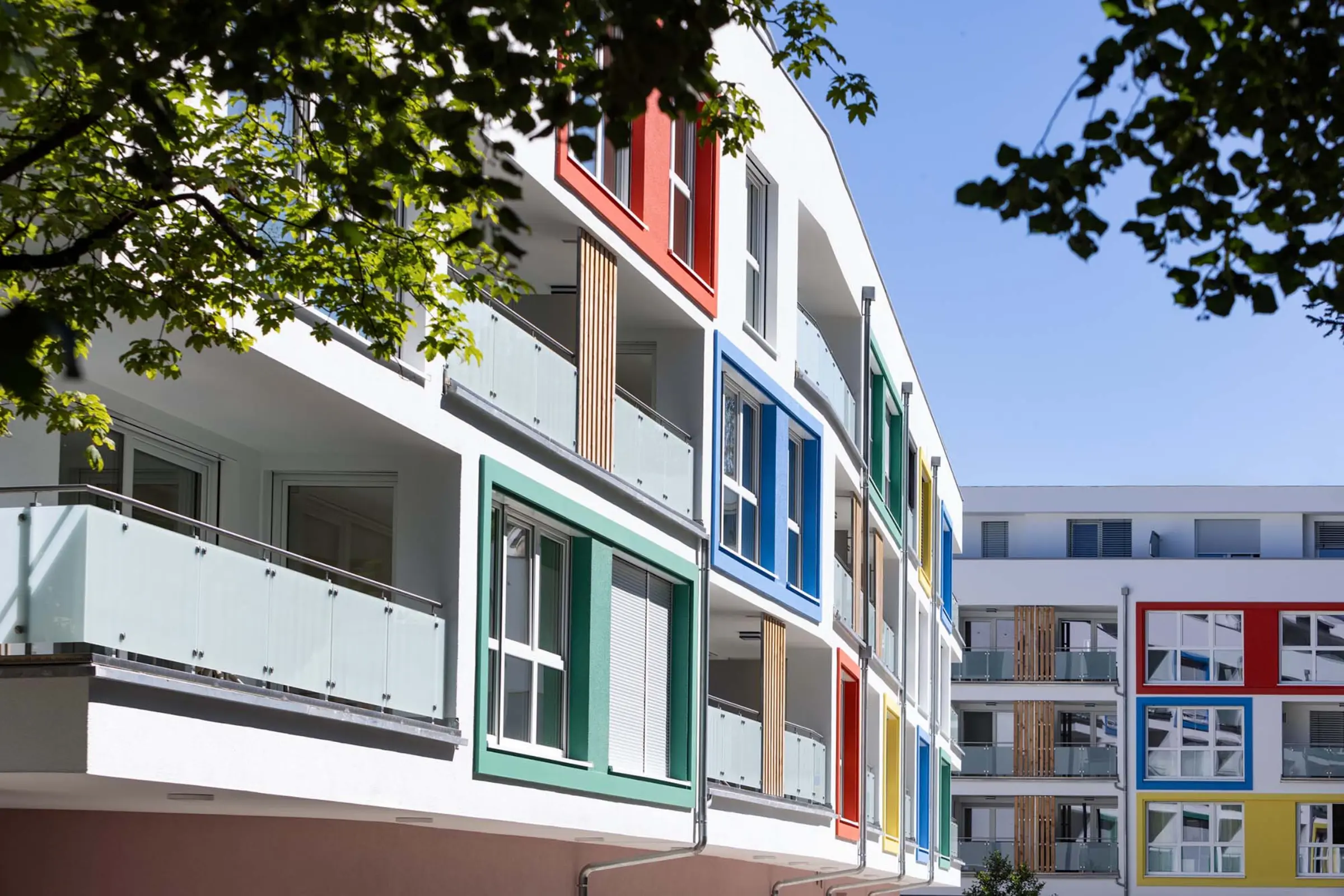 Außenaufnahme eines Wohngebäudes mit bunten Fensterumrandungen aus StoDeco Fassadenelementen