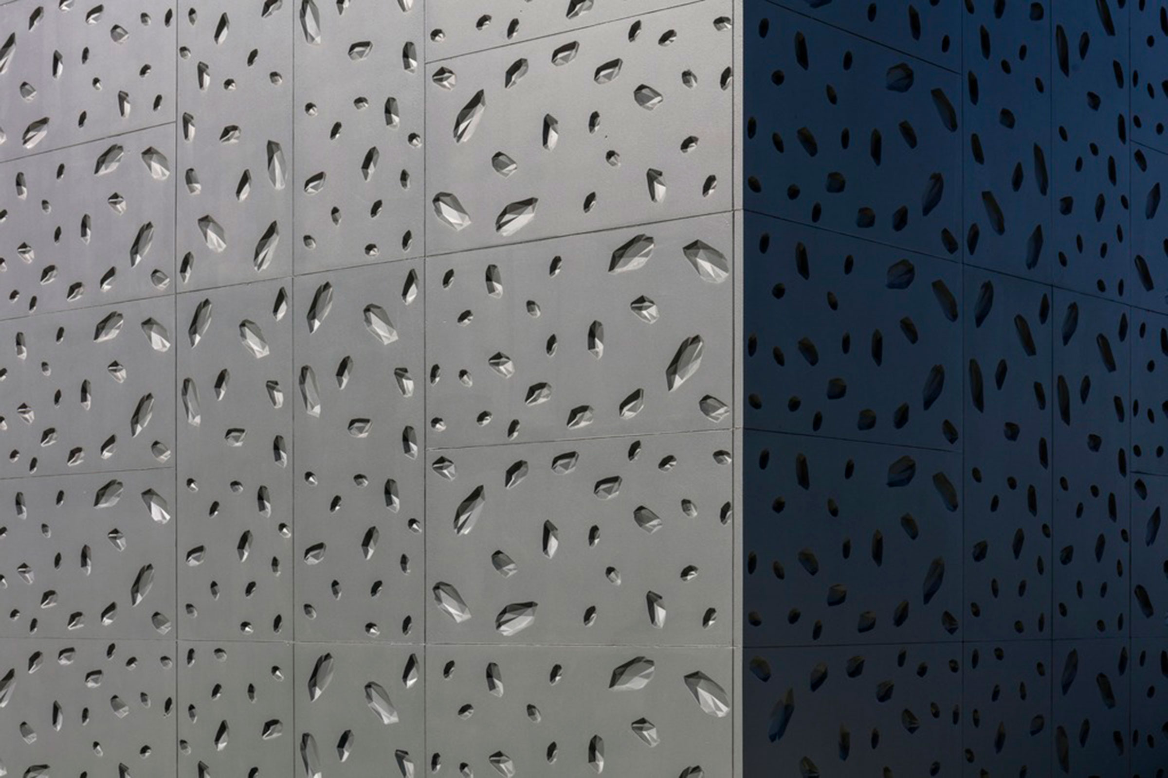 Die Fassadenplatten in einem dunklen, matten Farbton weisen zahlreiche komplex angeordnete Vertiefun