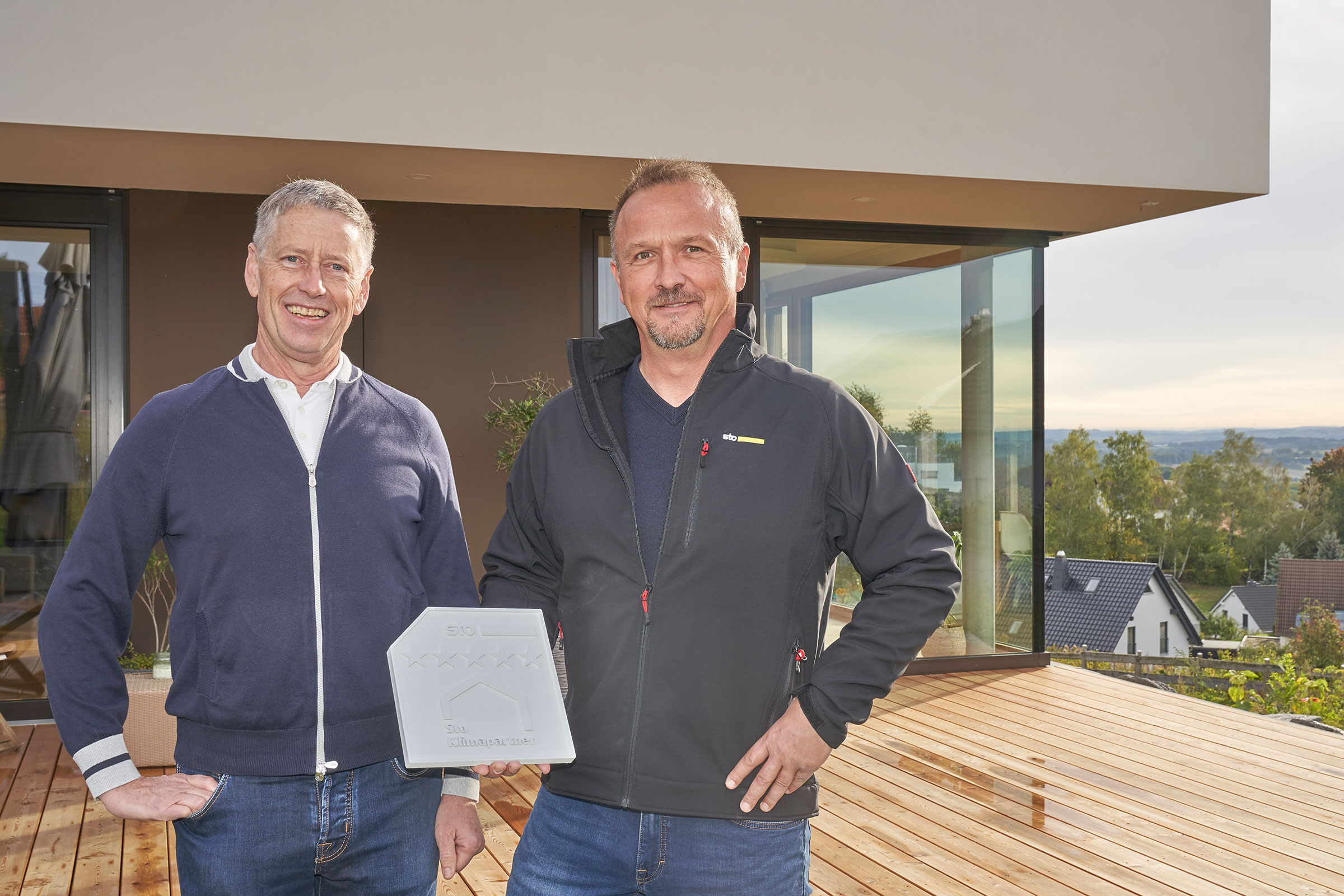 Zwei Männer im Gespräch vor einem Einfamilienhaus