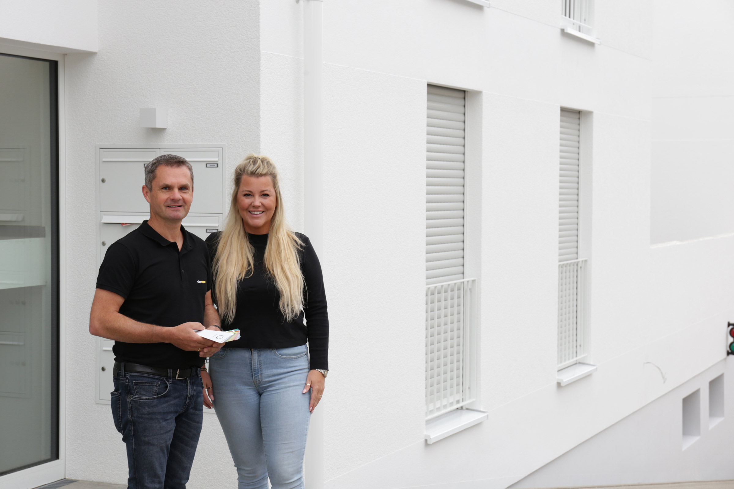 Mann und Frauen stehen vor einem weißen Gebäude