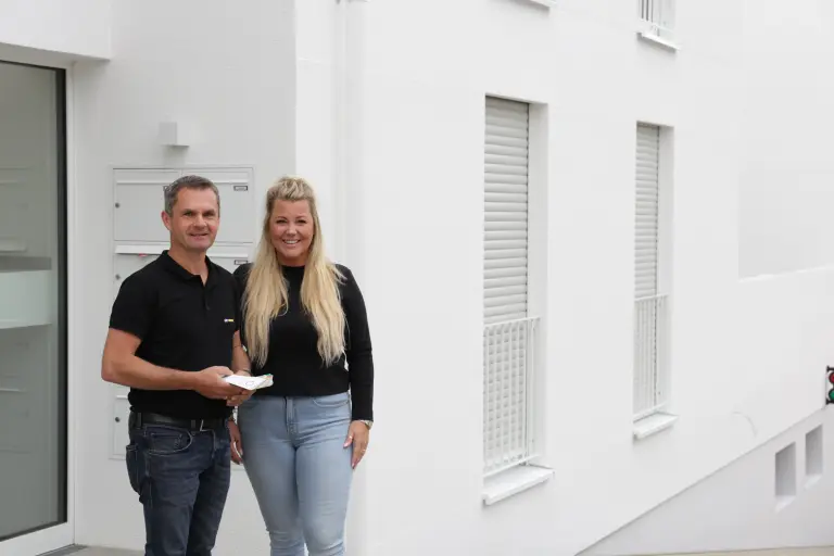 Mann und Frauen stehen vor einem weißen Gebäude