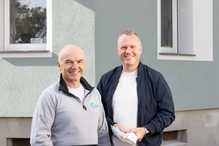 Zwei Männer im Gespräch vor einem Einfamilienhaus