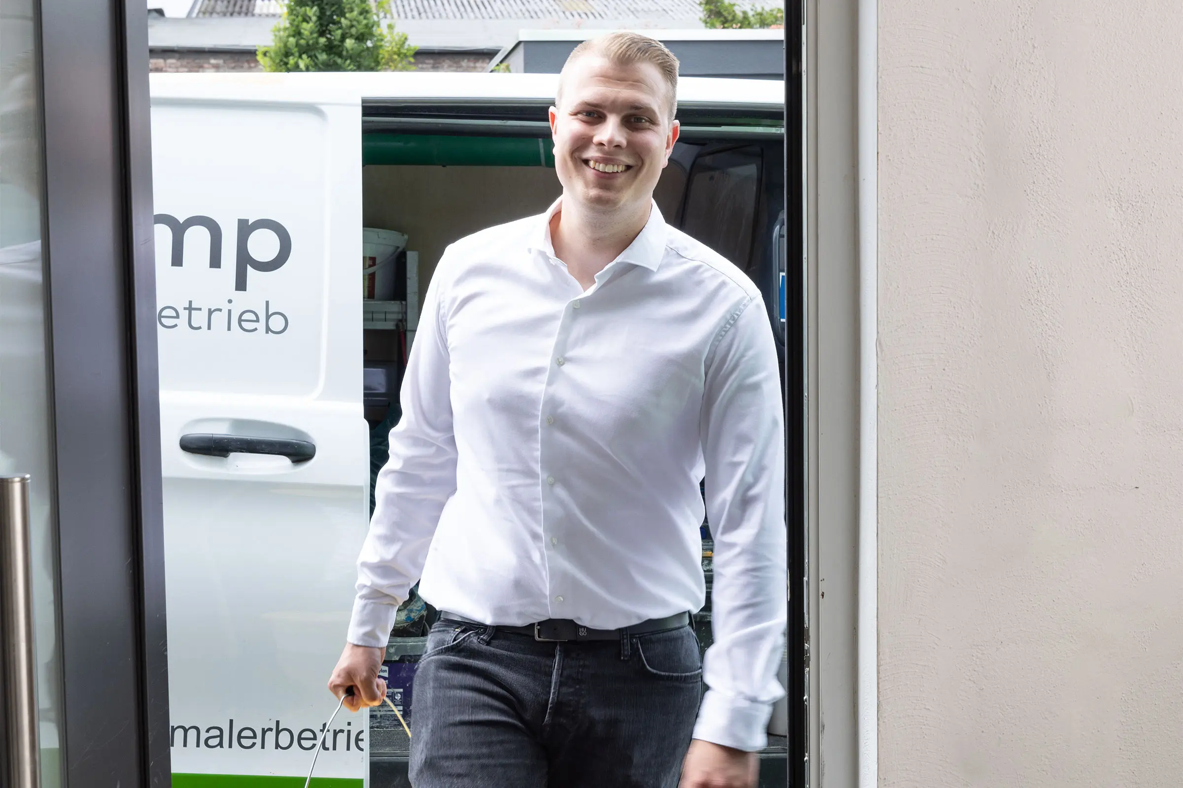 Darwin Langkamp betritt ein Firmengebäude mit einem Sto-Eimer in der Hand.