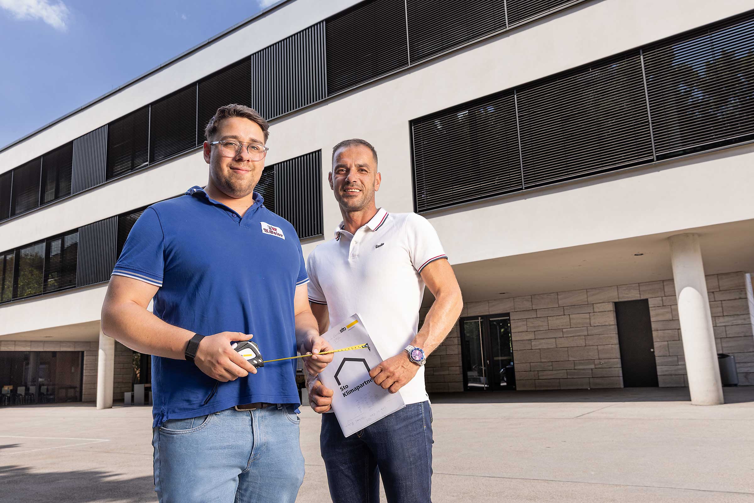 Zwei Männer im Gespräch vor einer Schule