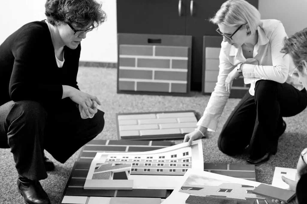 Zwei StoDesign-Mitarbeiterinnen beraten sich vor einer Wand mit Farb- und Materialkonzepten