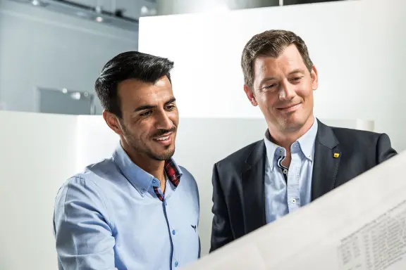 Beratungsgespräch Sto-Mitarbeiter und Kunde, sie schauen auf einen Bauplan, Compliance bei Sto