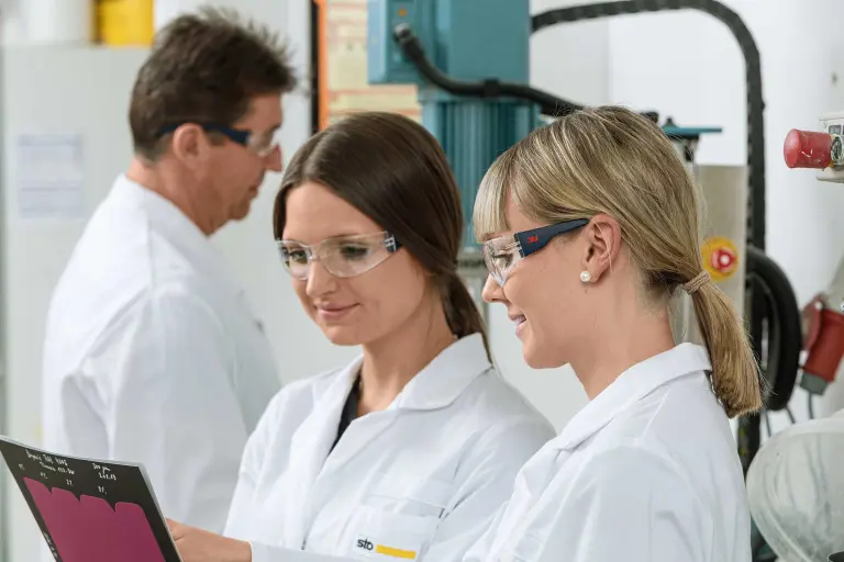 Zwei Sto-Kolleginnen aus der Forschung & Entwicklung schauen einen Laborbericht an, im Hintergrund ein weiterer F&E-Mitarbeiter; Bildquelle: © Martin Baitinger, Böblingen, DE